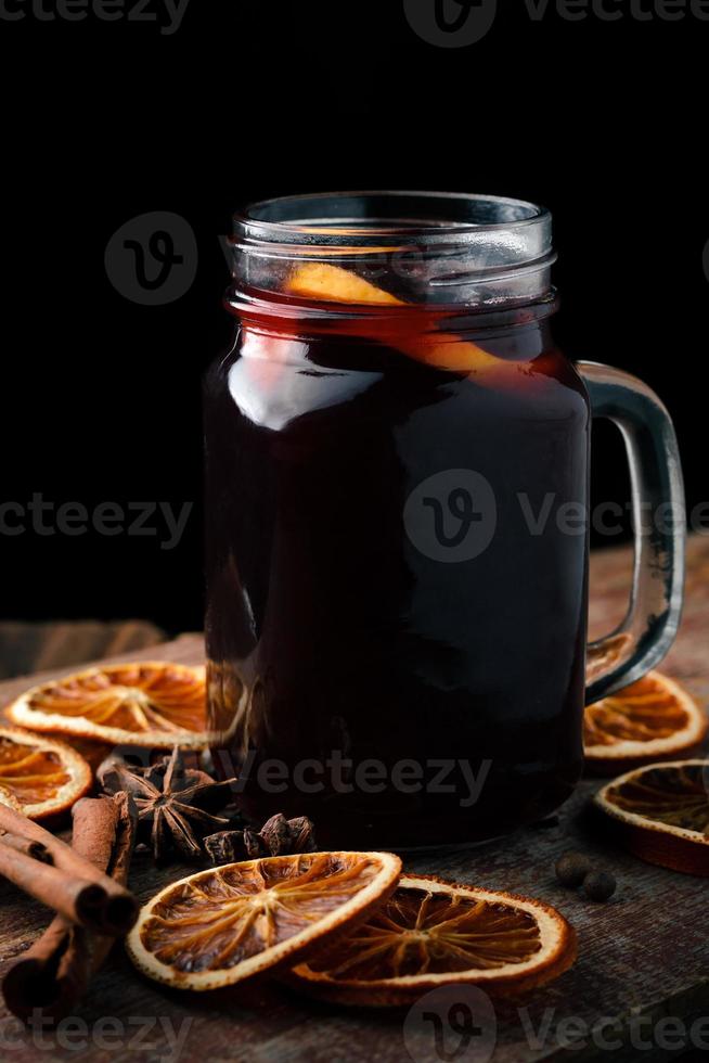 Glühwein mit Orangen, Zimtstangen und Anis auf einem Holztisch. foto