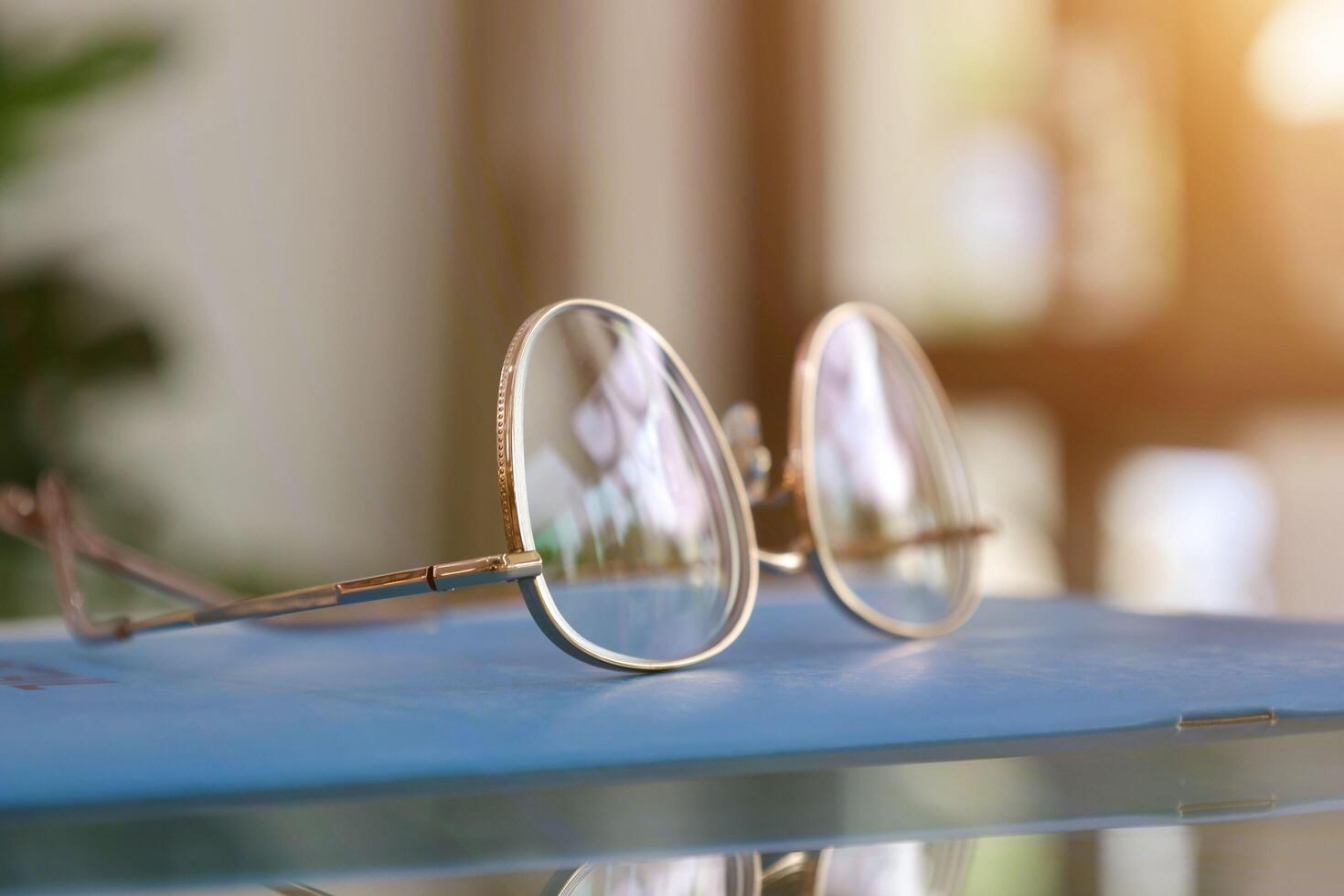 Brille auf Tisch, progressiv Linsen, Brille zum das Alten, Brille progressiv Linse, Brille progressiv Linse mit Sonnenlicht, Nahansicht von Brille auf verwischen Hintergrund, suchen durch Brille foto