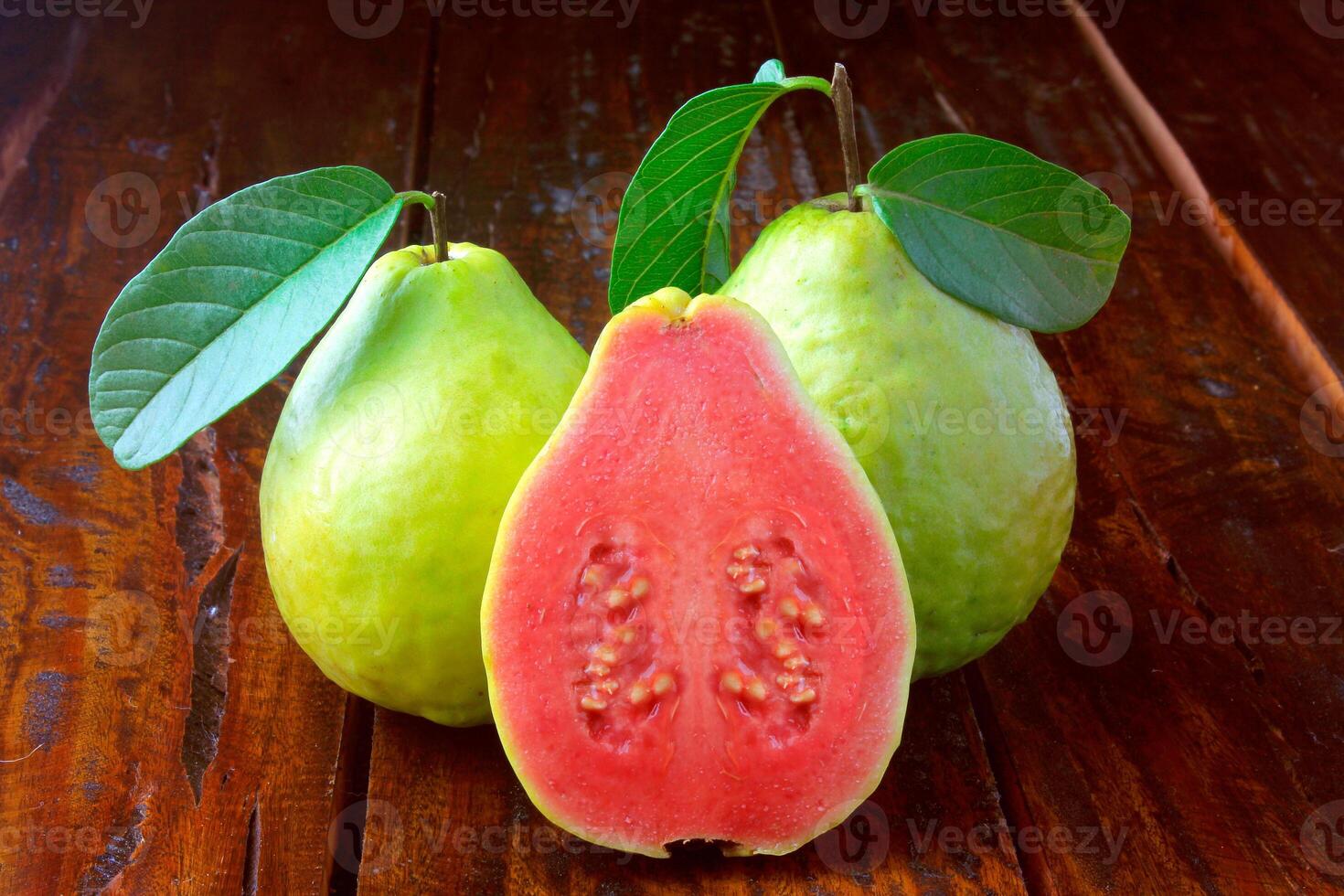Nahansicht Guave Frucht, Rosa, frisch, organisch, mit Blätter, ganze und geschnitten, auf rustikal hölzern Tabelle foto