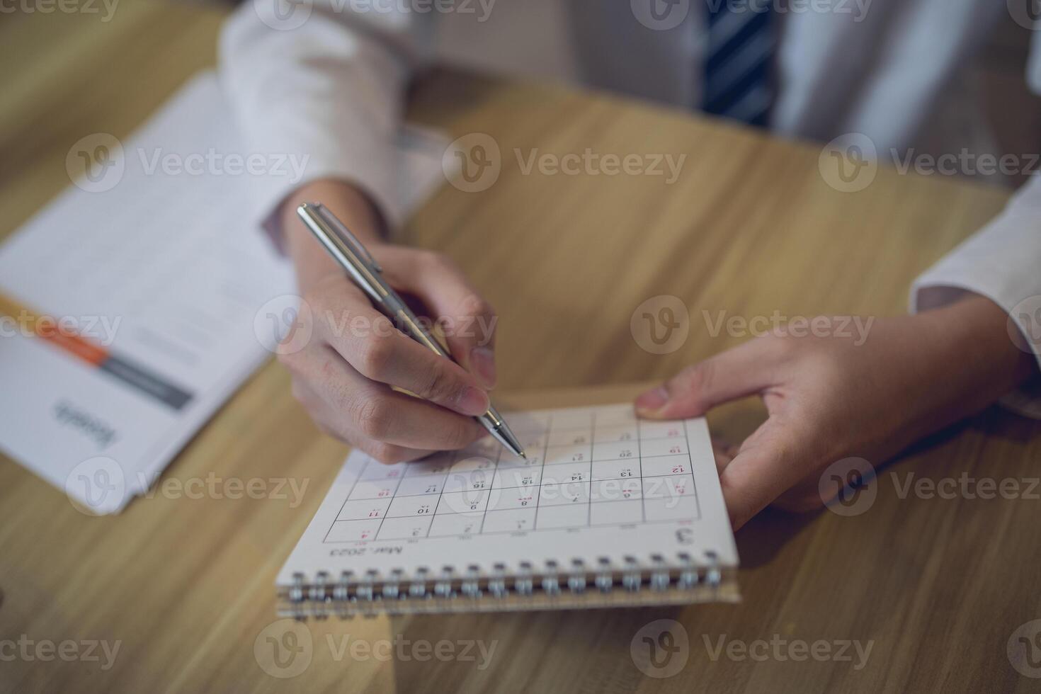 Fachmann Rahmen ein Zeitplan im ein Planer mit ein Stift, inmitten ein geschäftsorientiert Arbeitsplatz foto