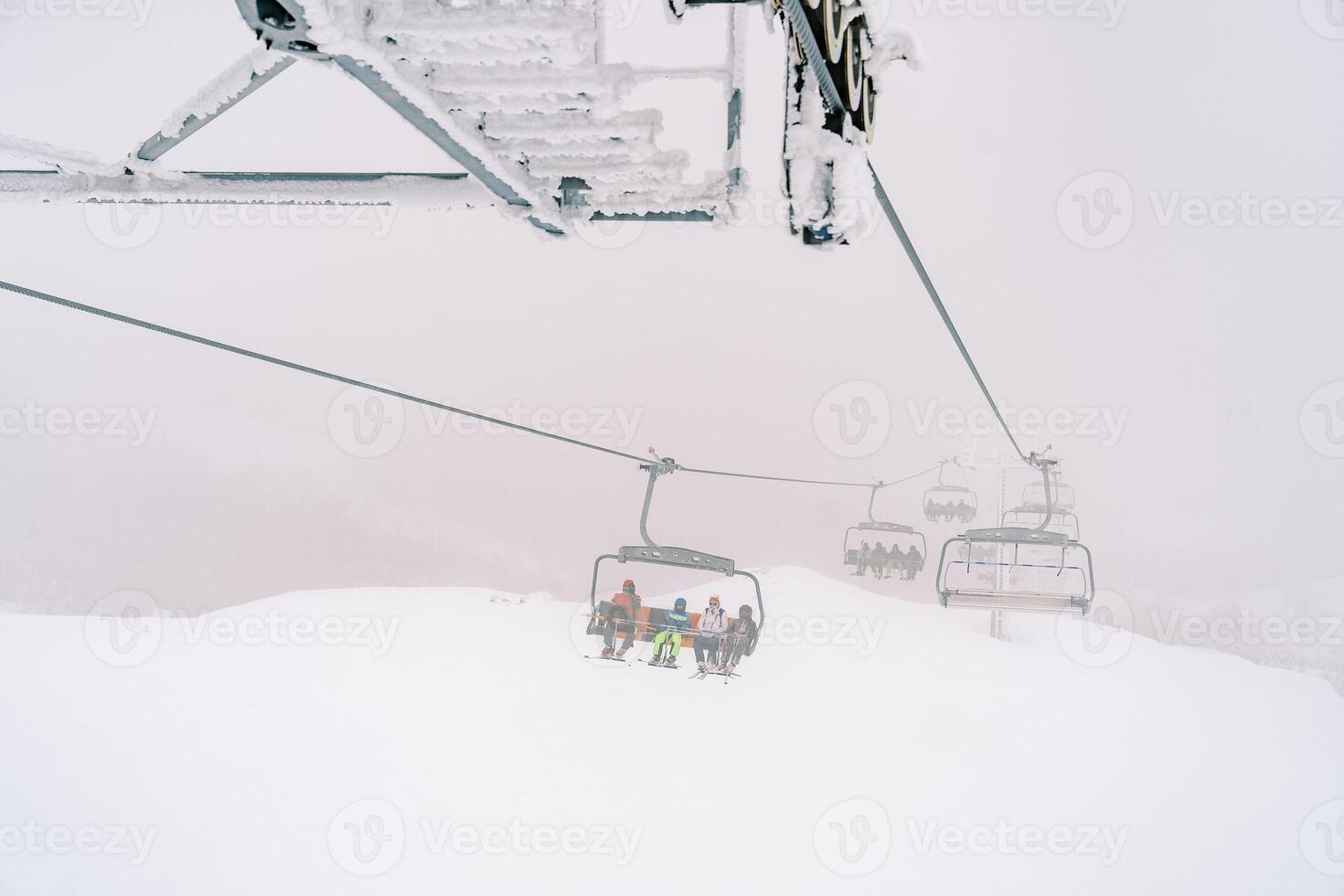 Viersitzer Sessellift mit Touristen bewegt sich durch das Nebel oben das Berghang foto