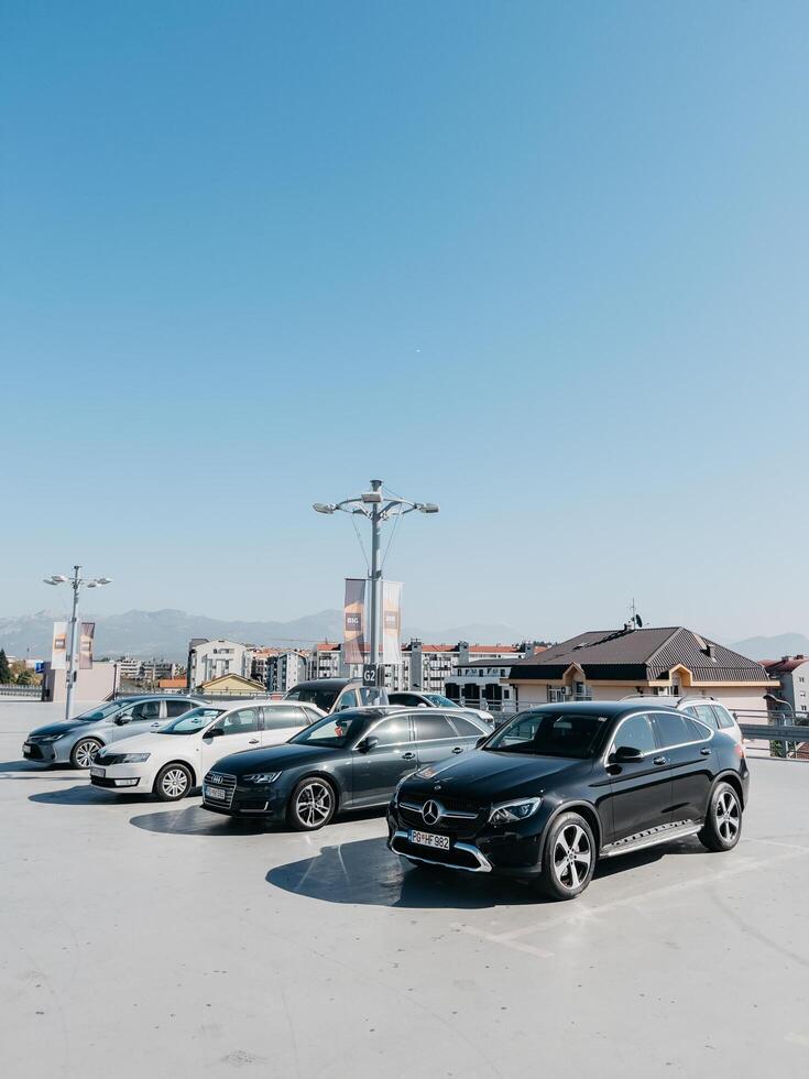 Podgorica, Montenegro - - 14 August 2023. verschiedene Autos Stand im ein öffnen Parkplatz Menge in der Nähe von das Häuser foto