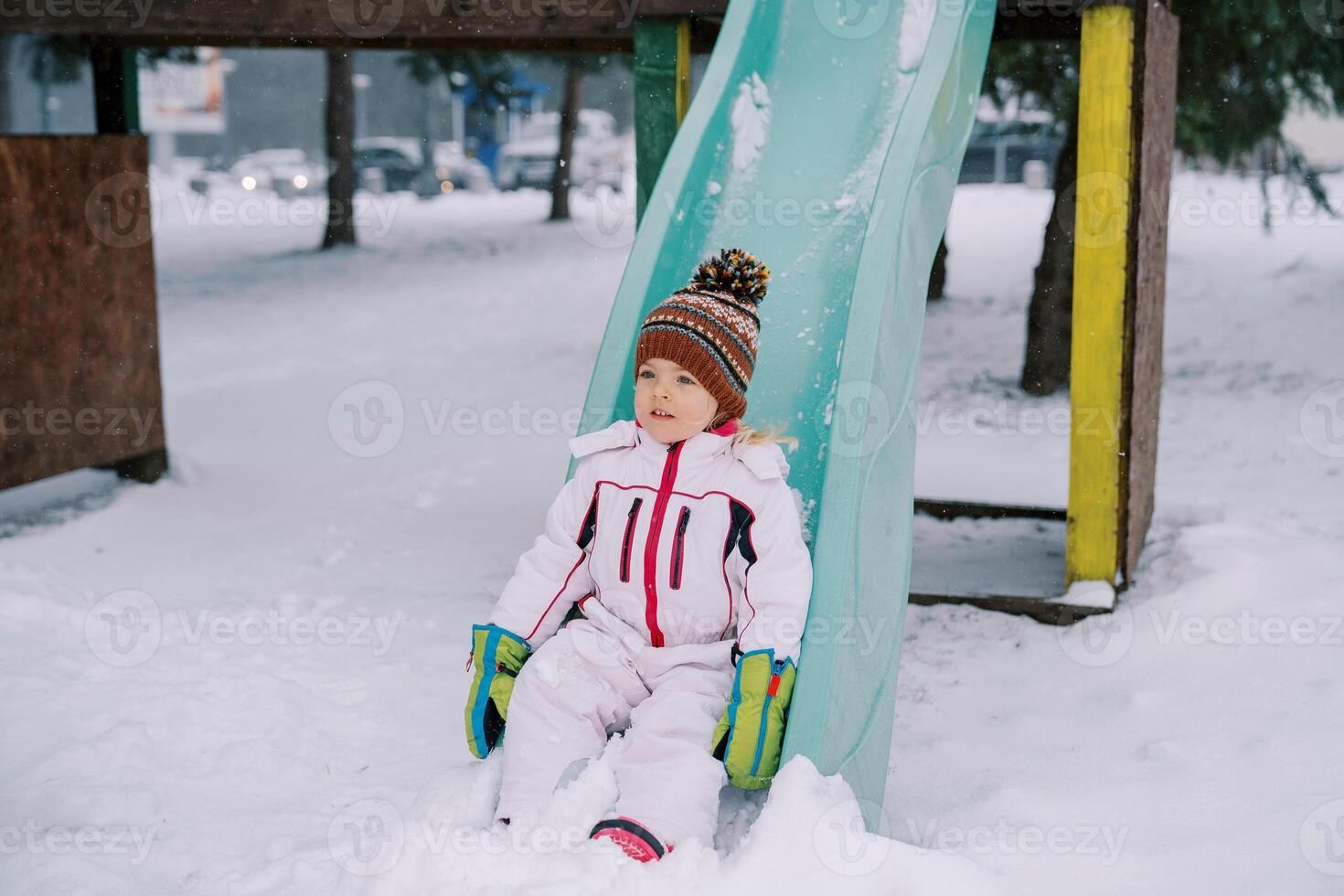 wenig Mädchen gleiten Nieder ein schneebedeckt bunt rutschen foto