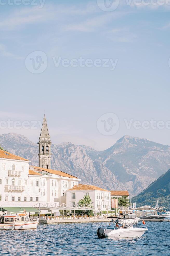 Yacht ist festgemacht aus das Küste von perast mit Blick auf uralt Häuser und das Glocke Turm von das Kirche von st. Nikolaus. Montenegro foto