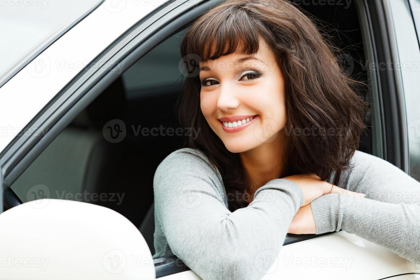 ziemlich Frau Treiber lächelnd zu Sie von das Weiß Auto foto