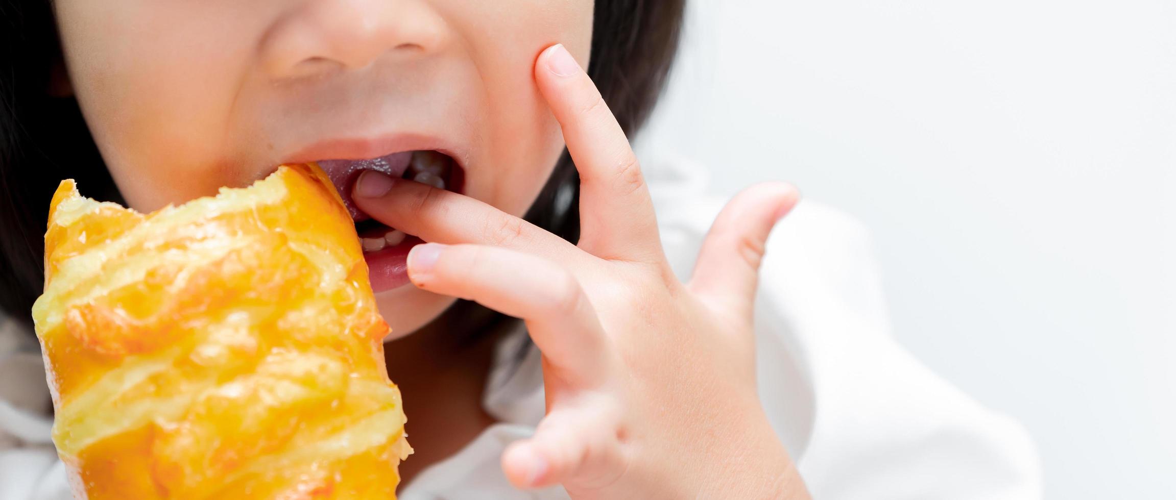 Kindergesicht leckte mit den Fingern den süßen Geschmack von Marmelade auf dem Toast, den sie hielt. Leerraum, um Text einzugeben. foto