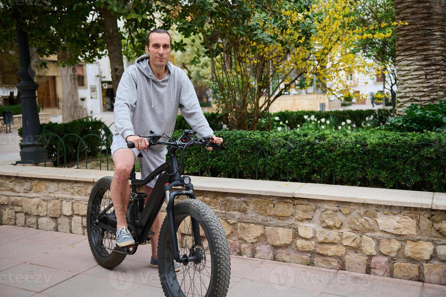 voll Länge Porträt von ein gut aussehend kaukasisch Mann mieten elektrisch Fahrrad, Reiten im das Stadt. Fahrrad Teilen Stadt Bedienung foto