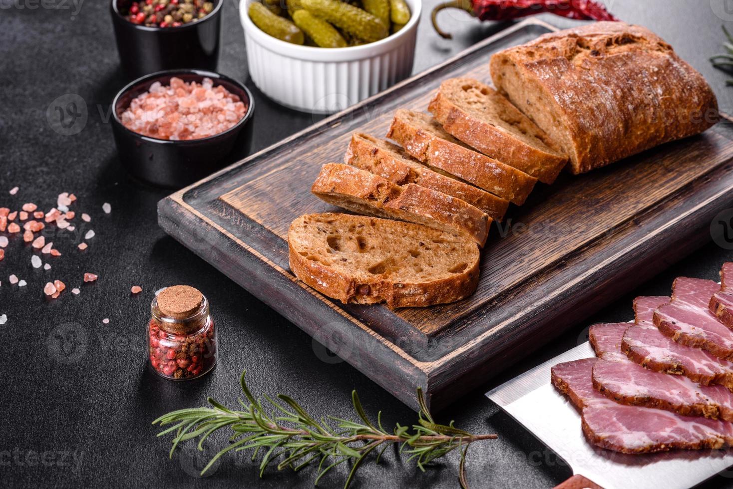 leckerer frischer Speck in Scheiben geschnitten mit Brot und Gemüse foto