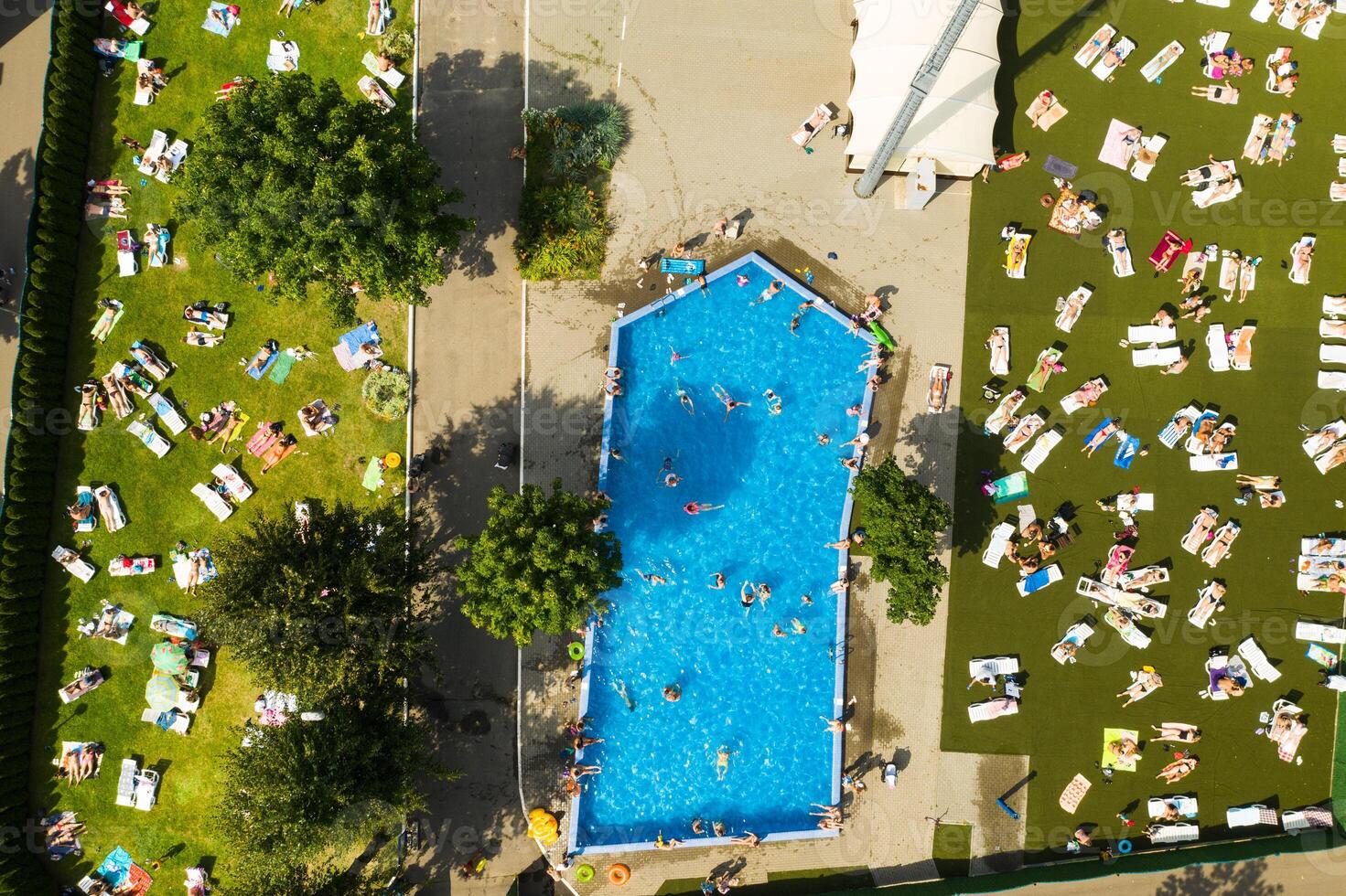 oben Aussicht von ein draussen Platz zum Menschen zu entspannen wo Dort ist ein Schwimmen Schwimmbad und ein Menge von Sonne Betten foto