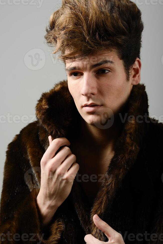 attraktiver junger Mann mit Pelzmantel mit moderner Frisur foto