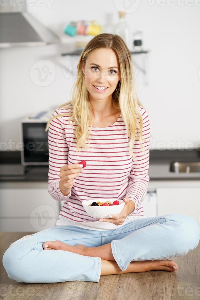 Kaukasische Frau, die eine Vorspeise mit Nüssen, Himbeeren und Brombeeren isst. foto