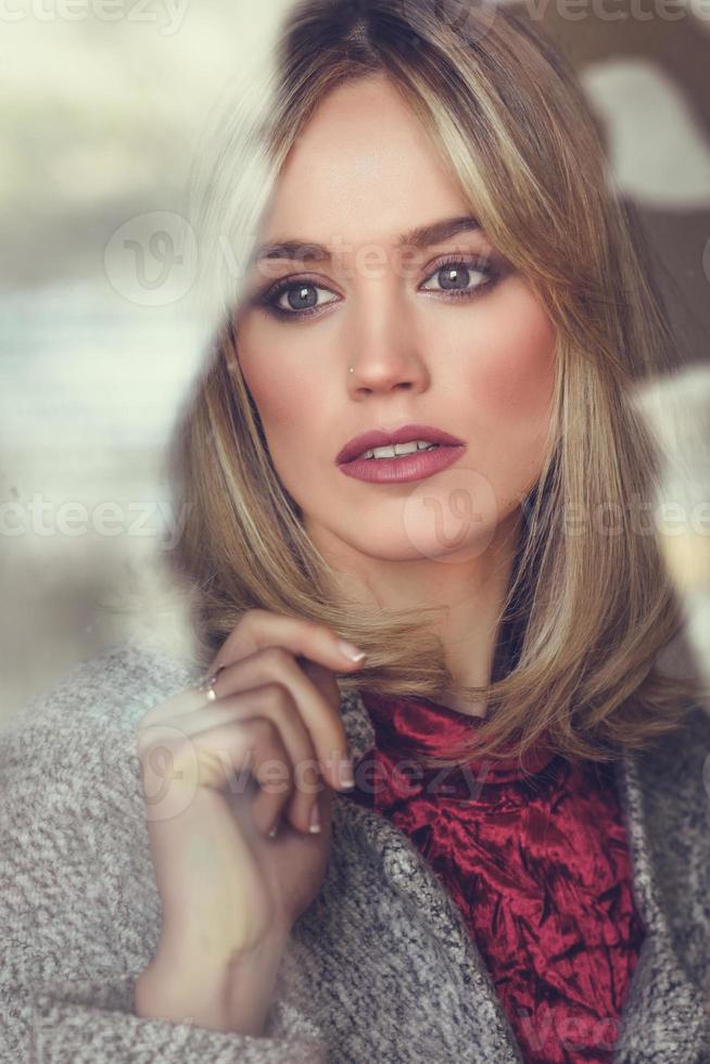 nachdenkliche junge blonde Frau mit verlorenen Augen aus dem Fenster foto
