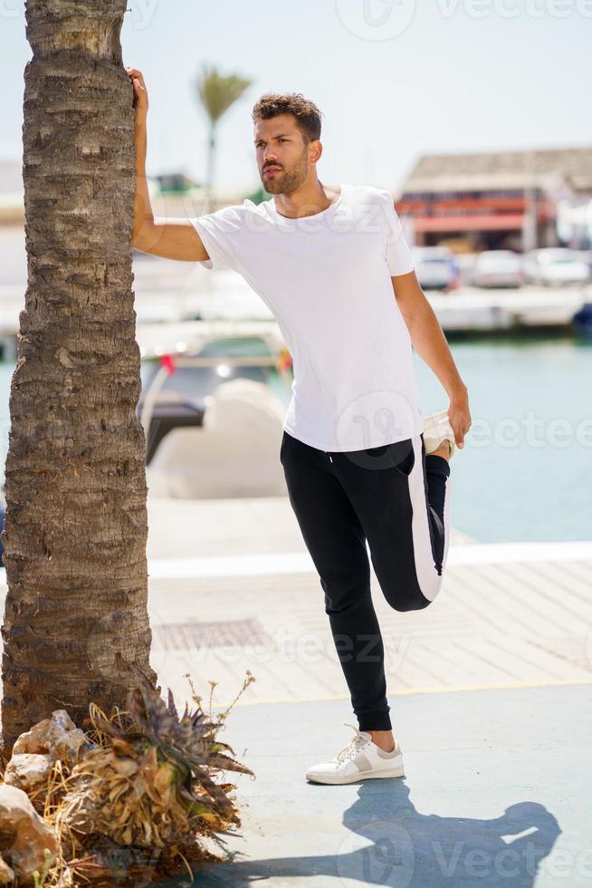 Mann streckt sich nach dem Training in einem Hafen foto