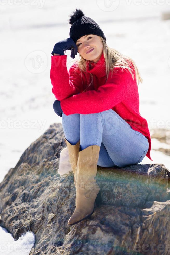 junge Frau sitzt auf einem Felsen in den schneebedeckten Bergen im Winter, in Sierra Nevada, Granada, Spanien. foto