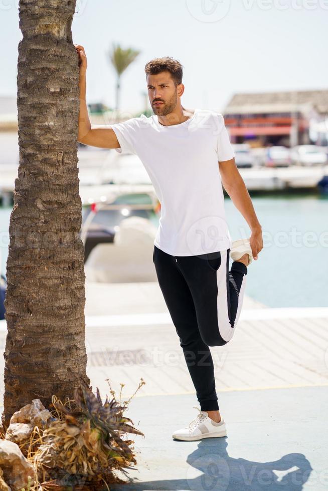 Mann streckt sich nach dem Training in einem Hafen foto