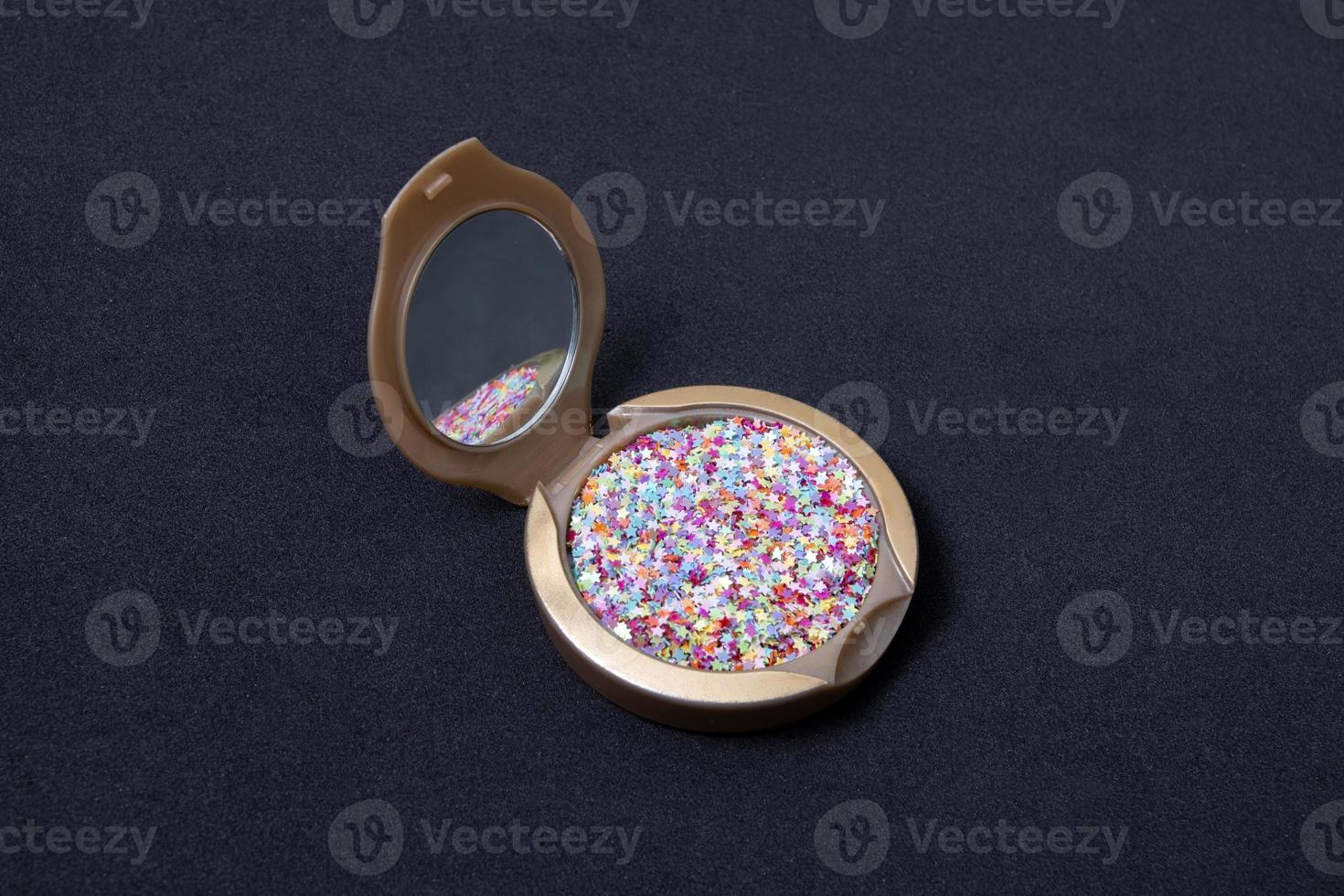 Make-up-Puder und Kosmetikpinsel mit Glitzersternen auf schwarzem Hintergrund foto