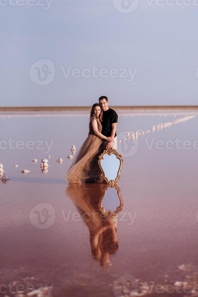 Mädchen und ein Mann am Ufer eines rosa Salzsees foto