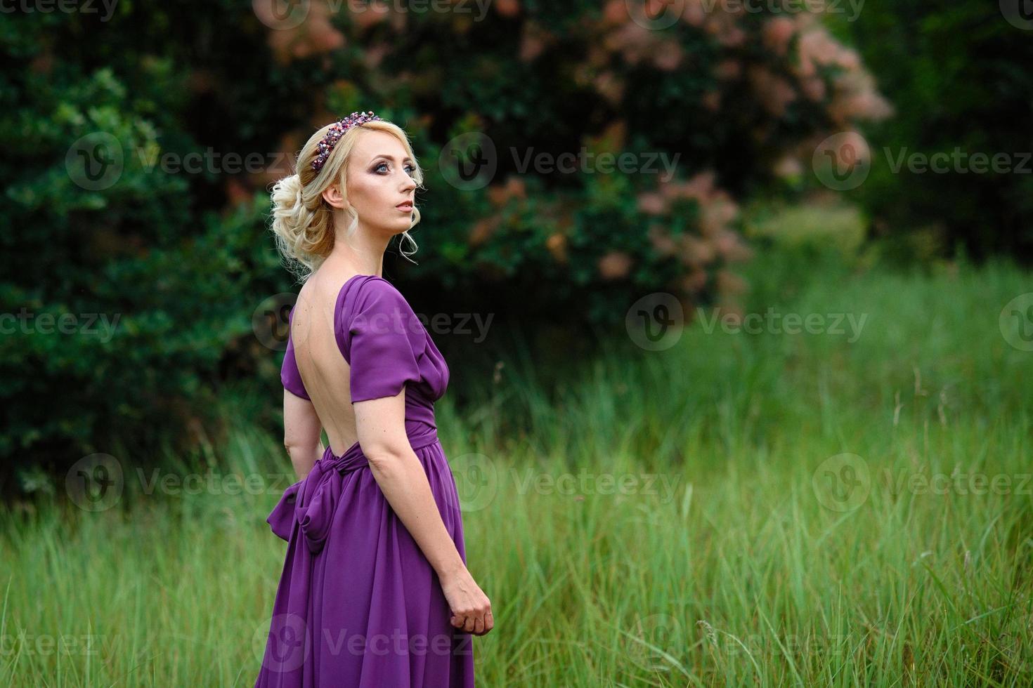 Mädchenmodell Blondine in einem lila Kleid mit einem Blumenstrauß foto