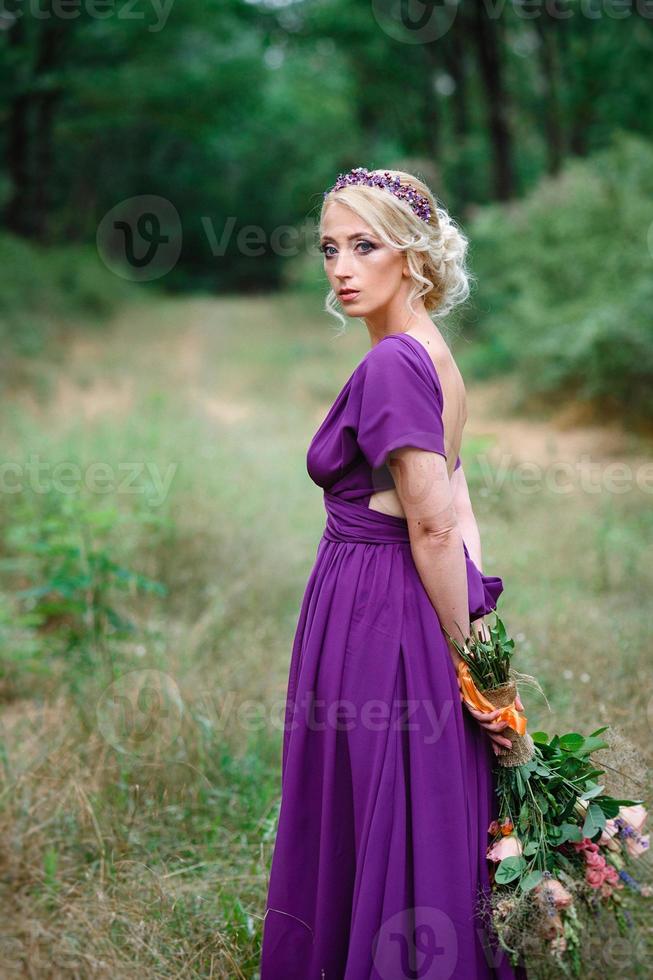 Mädchenmodell Blondine in einem lila Kleid mit einem Blumenstrauß foto