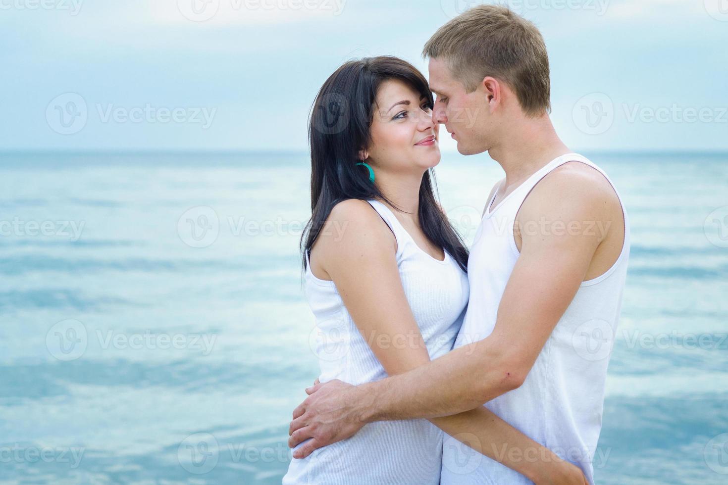 Typ und ein Mädchen in Jeans und weißen T-Shirts am Strand foto