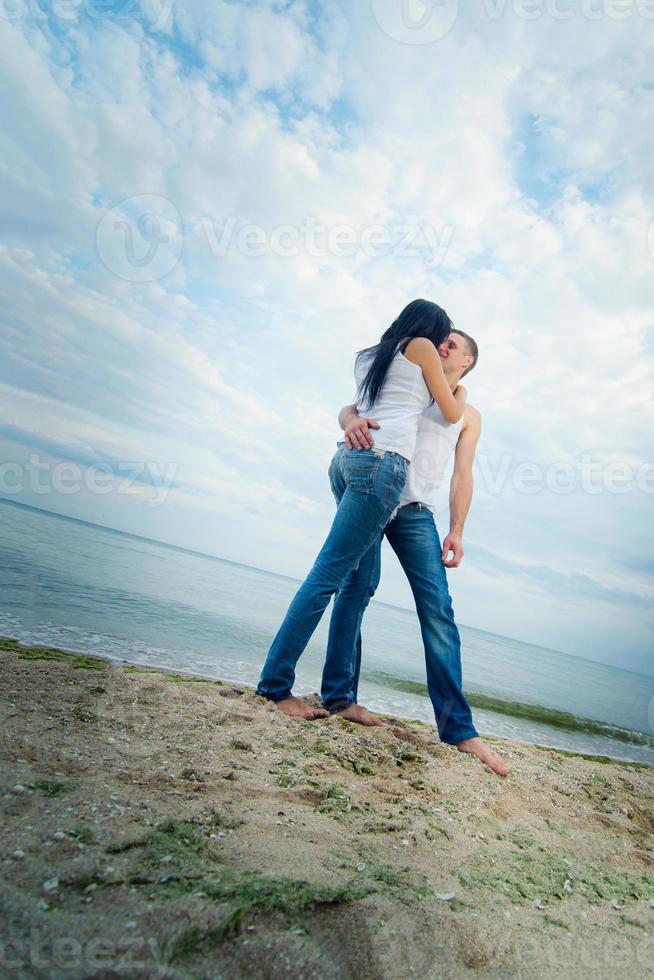 Typ und ein Mädchen in Jeans und weißen T-Shirts am Strand foto