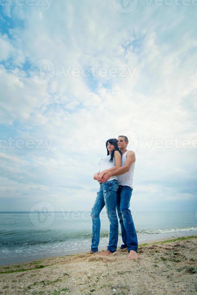 Typ und ein Mädchen in Jeans und weißen T-Shirts am Strand foto