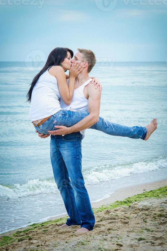 Typ und ein Mädchen in Jeans und weißen T-Shirts am Strand foto