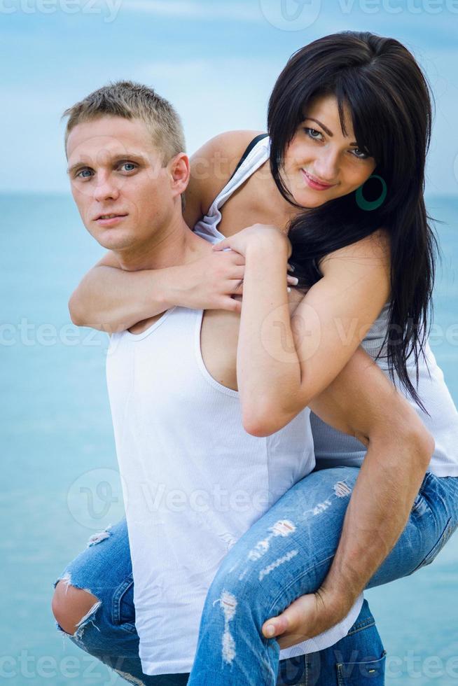 Typ und ein Mädchen in Jeans und weißen T-Shirts am Strand foto