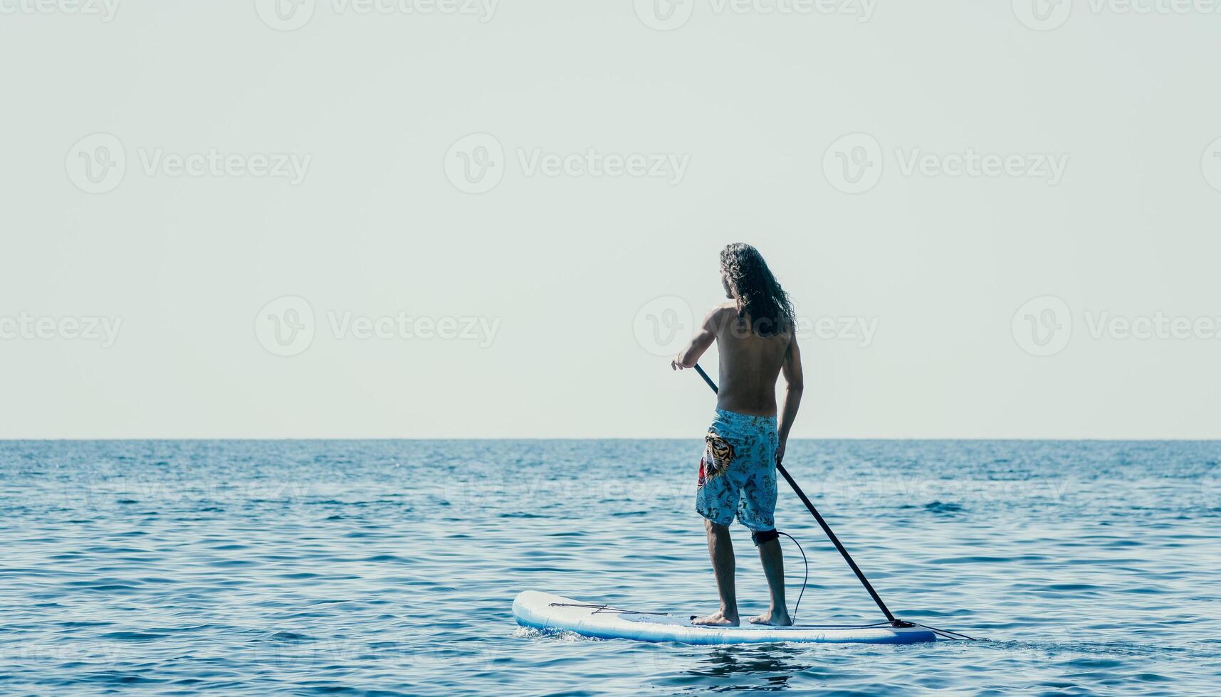 Mann sup Meer. stark sportlich Mann lernt zu Paddel sup Stehen auf Tafel im öffnen Meer Ozean auf sonnig Tag. Sommer- Urlaub Ferien und Reise Konzept. Antenne Sicht. schleppend Bewegung foto