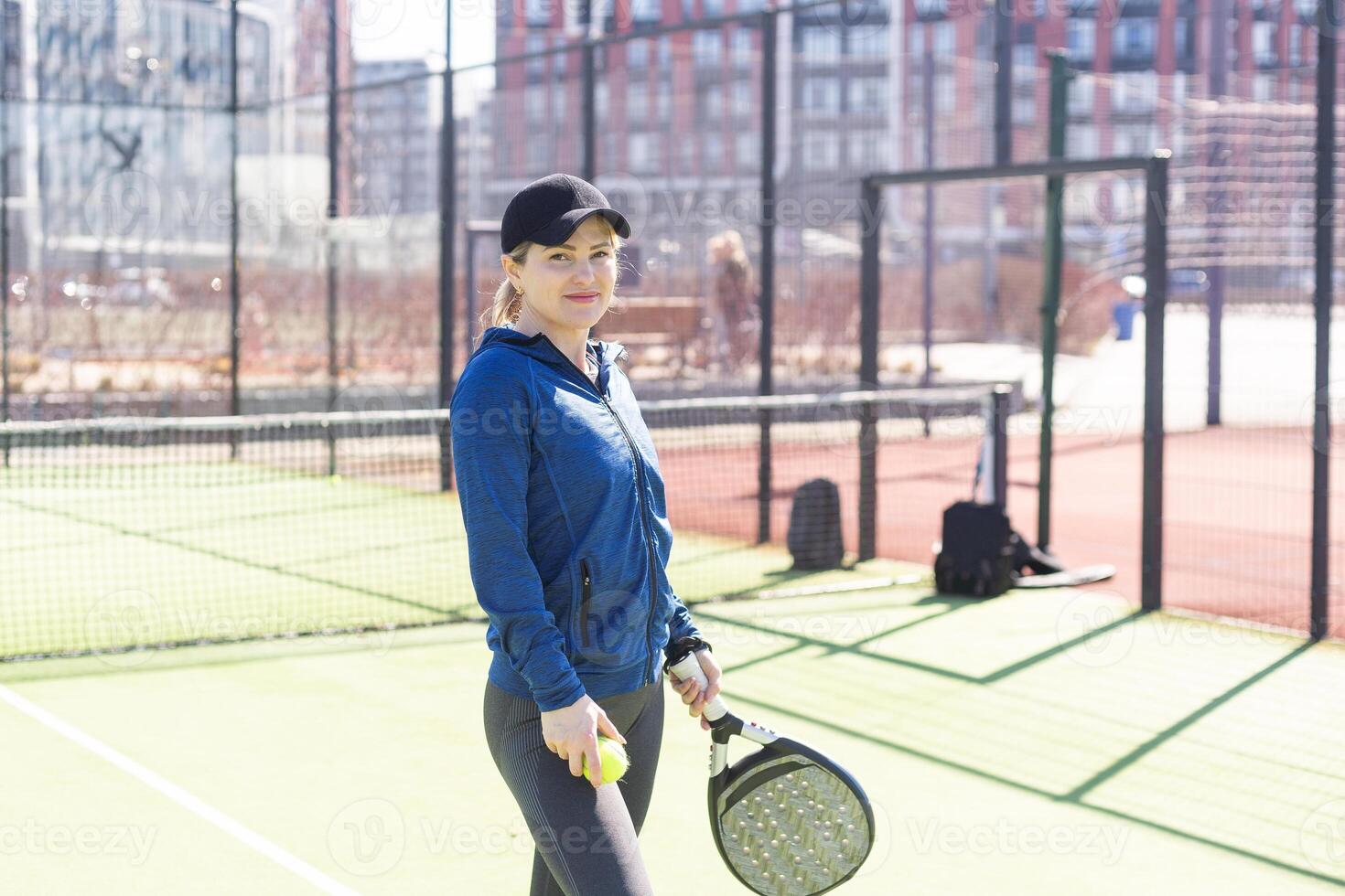 einer Frau mit Schläger und Ball hinter das Netz im Paddel Tennis Gericht bereit zum Ausbildung foto