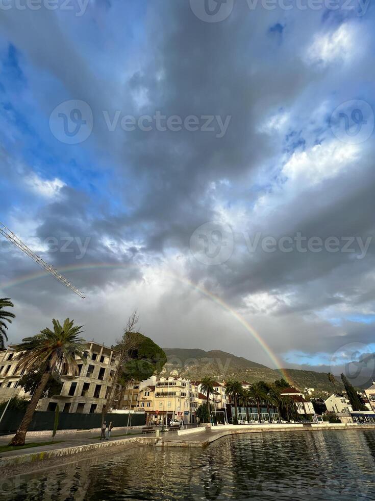 Regenbogen Über das Meer Küste von ein Resort Stadt, Dorf in der Nähe von das Berge foto