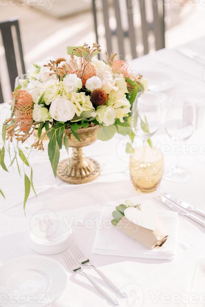 Strauß von Blumen steht auf ein festlich Tabelle Nächster zu ein Einladung saftig im ein Papier Tasse mit ein Herz foto