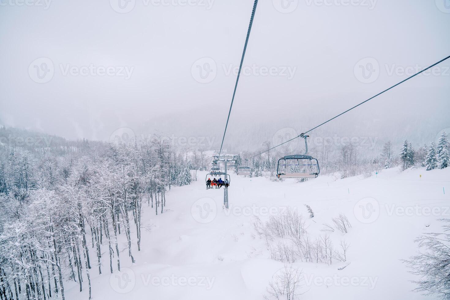 Skifahrer Reiten Über schneebedeckt Berge auf ein Viersitzer Sessellift foto