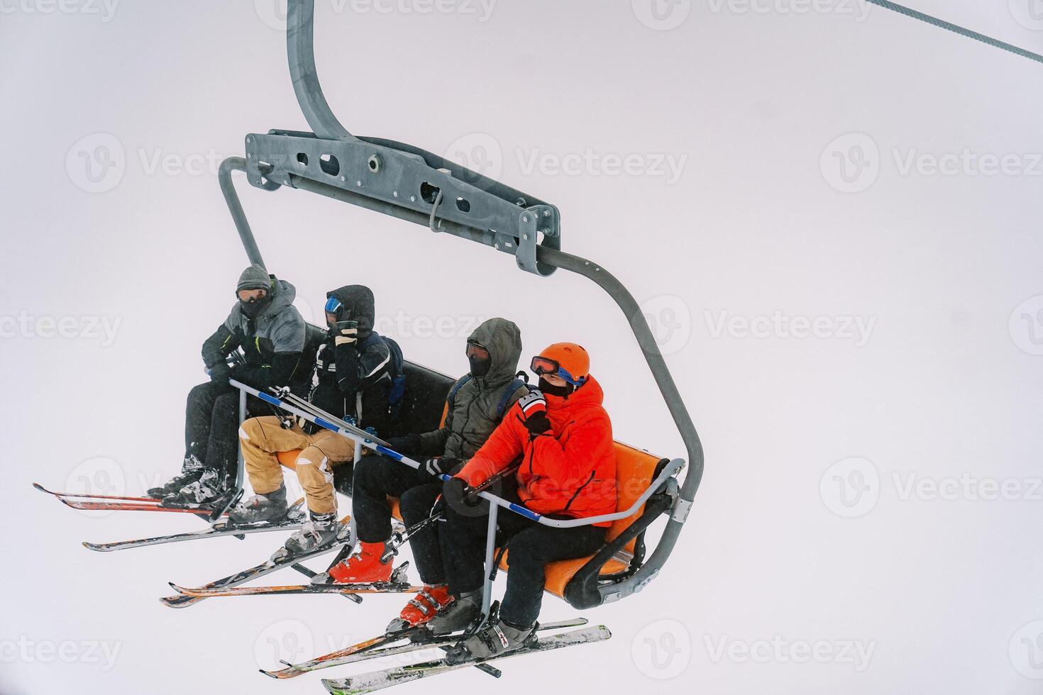 Touristen im Ski Anzüge und Brille Reiten ein Sessellift oben ein nebelig Berg foto