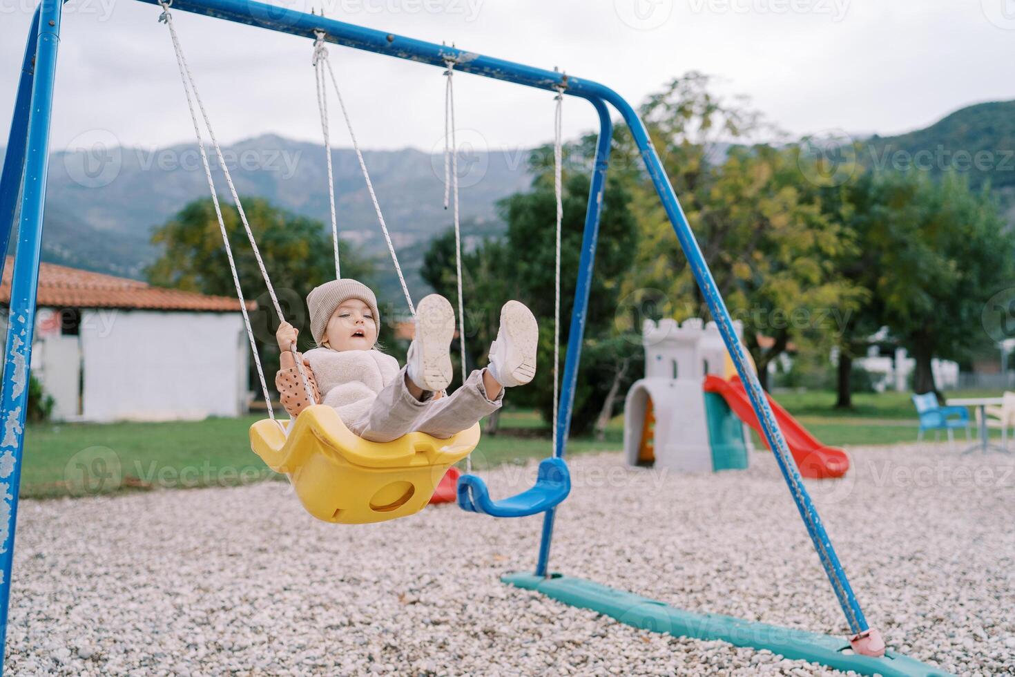 wenig Mädchen Schaukeln auf ein Seil schwingen auf ein Spielplatz im ein Grün Park foto