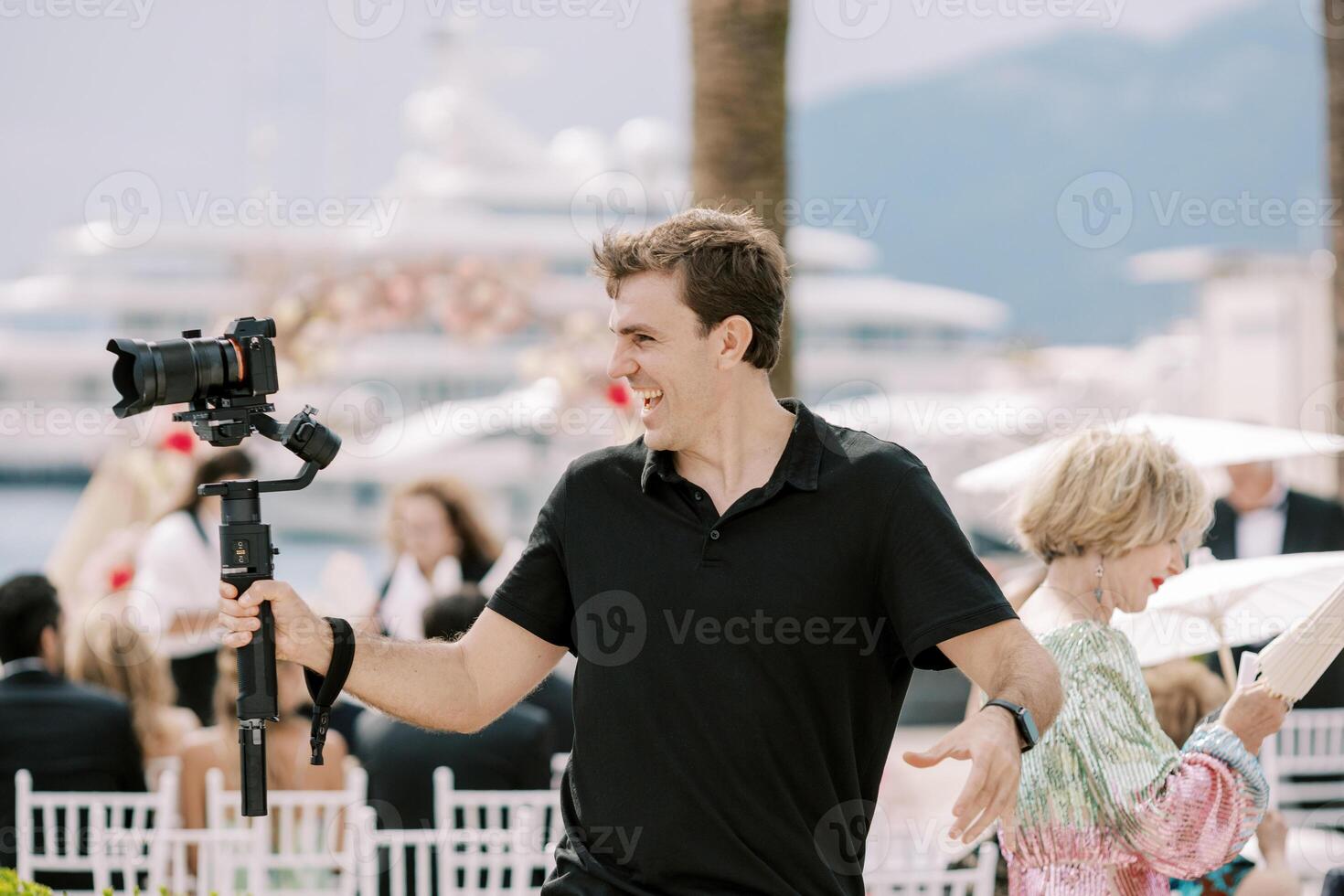 lächelnd Fotograf nehmen Bilder von ein Hochzeit Zeremonie während halten ein Digital Kamera im seine Hand auf ein Stand foto