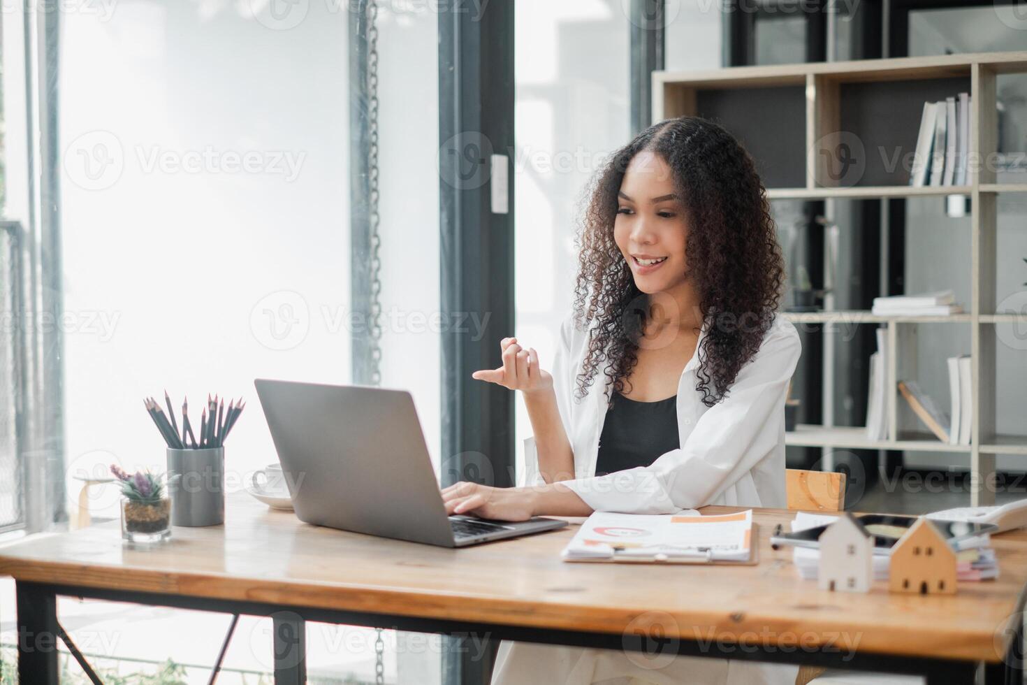animiert jung Geschäftsfrau einnehmend im ein lebhaft Konversation während ein virtuell Treffen im ein sonnig, modern Arbeitsplatz. foto