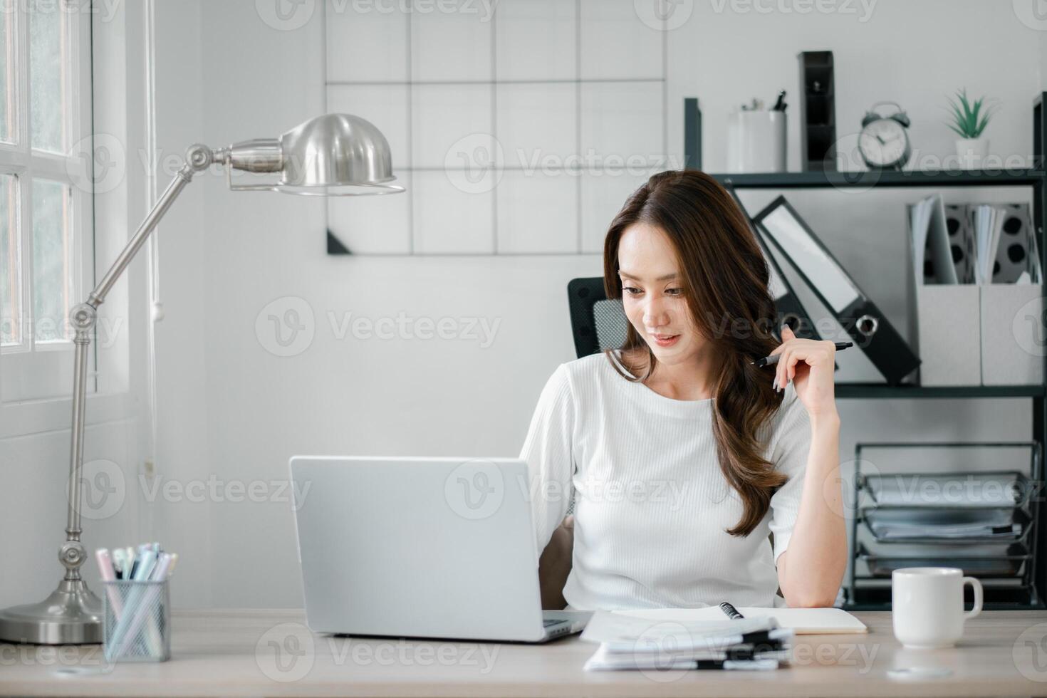 jung Frau Arbeiten auf ihr Laptop im ein gut organisiert Zuhause Büro Umfeld, ausstellen Konzentration und Professionalität. foto