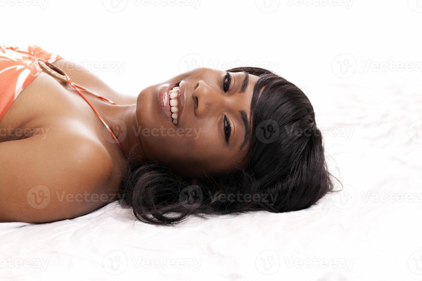 lächelnd jung schwarz Frau liegend auf Fußboden foto