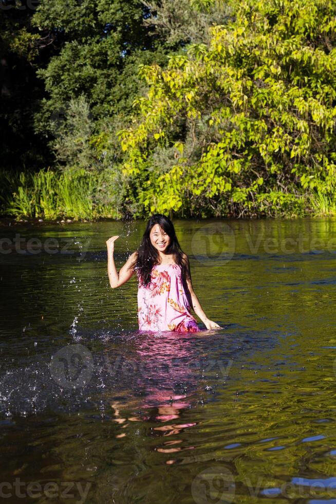 jung japanisch Frau planschen Fluss Kleid lächelnd foto