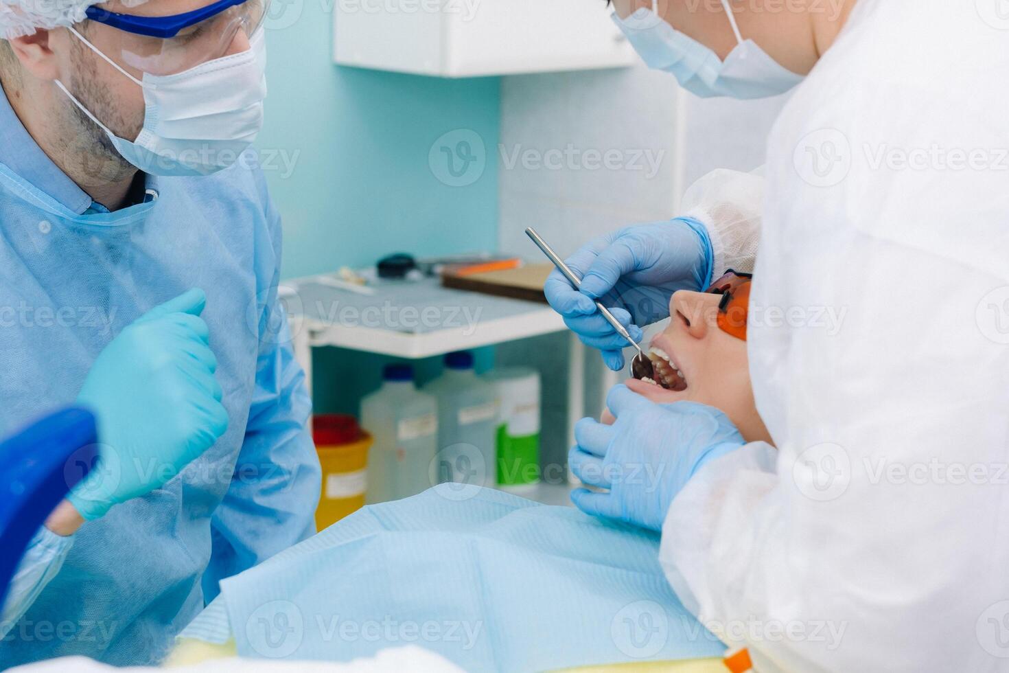 ein männlich Zahnarzt mit Dental Werkzeuge Bohrer das Zähne von ein geduldig mit ein Assistent. das Konzept von Medizin, Zahnheilkunde und Gesundheitswesen foto