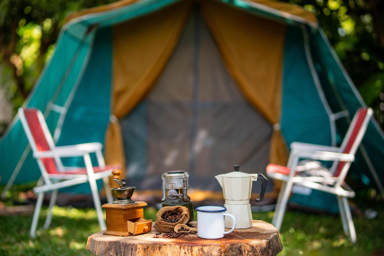 selektiv Fokus von Jahrgang Kaffee einstellen auf das alt hölzern Tabelle im Vorderseite von das retro Kabine Zelt, retro Stühle, Gruppe von Camping Zelte, und Sanft Fokus. foto