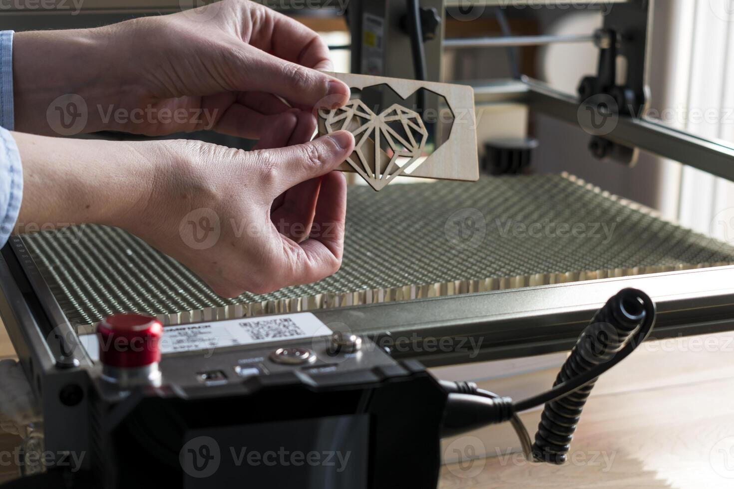 Laser- Gravur und Schneiden, Frau halten ein Beispiel von ein Schnitt aus hölzern Herz foto