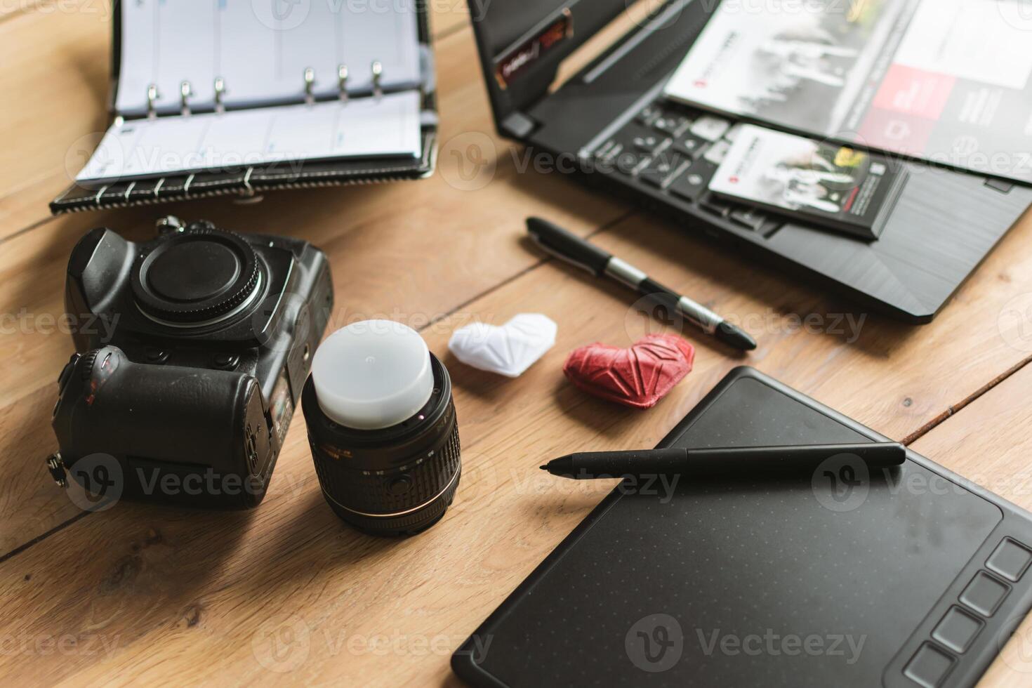 Grafik Designer Arbeitsplatz mit DSLR, Linse, Laptop, Agenda, Stift und 3d Objekte foto