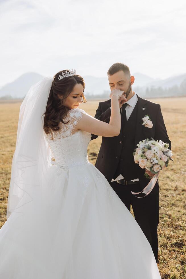 das Bräutigam Küsse das Braut Hand. Hochzeit Foto von ein Paar im Liebe. ein jung und gut aussehend Mann küssen seine Ehefrauen Hand mit ein Gold Ring, vorschlagen.