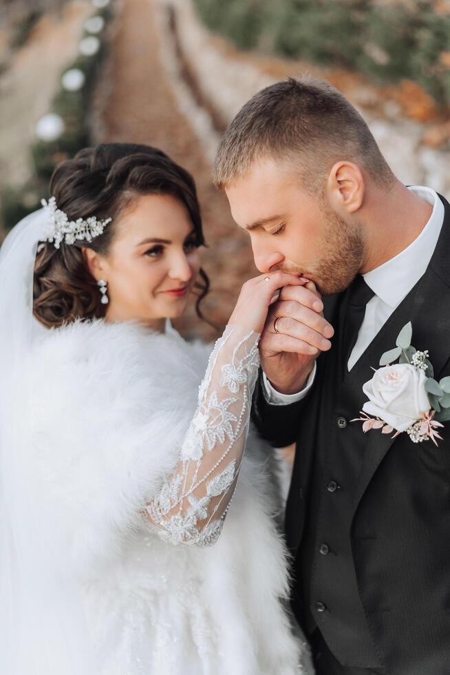 das Bräutigam Küsse das Braut Hand. Hochzeit Foto von ein Paar im Liebe. ein jung und gut aussehend Mann küssen seine Ehefrauen Hand mit ein Gold Ring, vorschlagen.