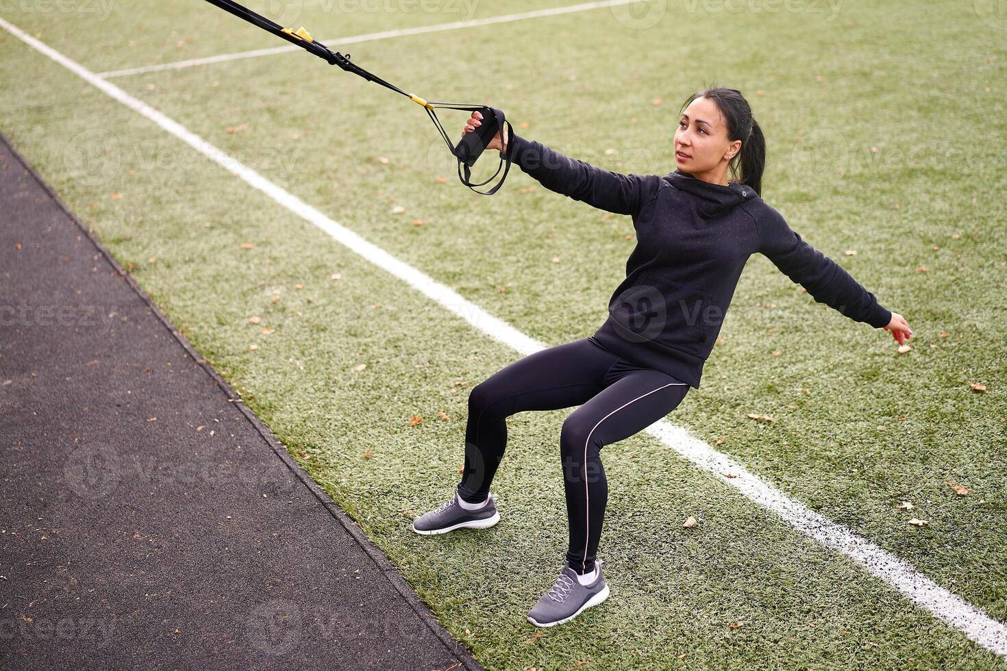 Mädchen Athlet funktional Ausbildung auf Sportplatz. gemischt Rennen jung Erwachsene Frau tun trainieren mit Suspension System. gesund Lebensstil. Dehnen draußen Spielplatz. foto