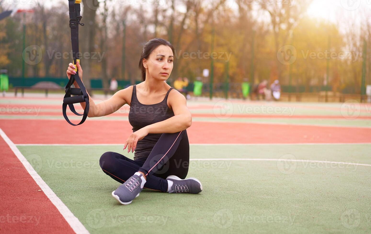 Mädchen Athlet funktional Ausbildung auf Sportplatz. gemischt Rennen jung Erwachsene Frau tun trainieren mit Suspension System. gesund Lebensstil. Dehnen draußen Spielplatz. foto