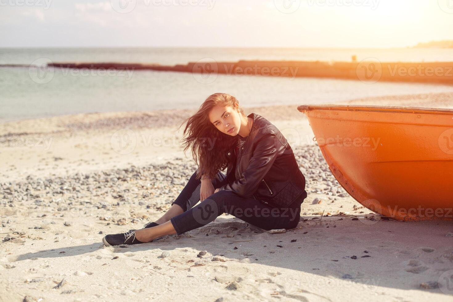 ein Mädchen seitwärts in der Nähe von ein rot Boot auf das Strand durch das Meer foto