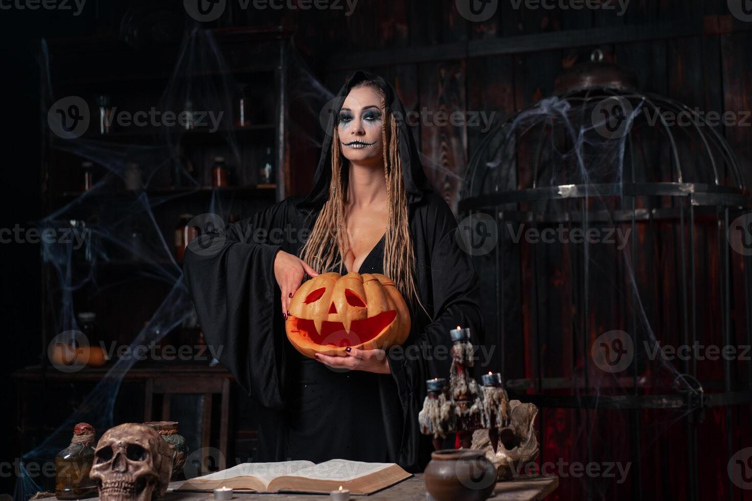 Halloween Konzept. schwarz Hexe halten Halloween Kürbis mit geschnitzt smiley Gesicht im Hand Stehen dunkel Zimmer foto